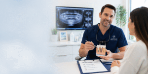 Dentist explaining the dental implant consultation process to a patient in Weston using a tooth model and digital dental scans.